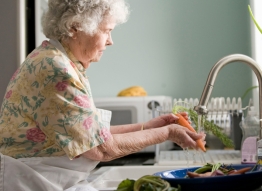 Photo of elderly women washing vegetables at a kitchen sink